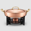 Copper pot with gold handles on a stand against a light gray background