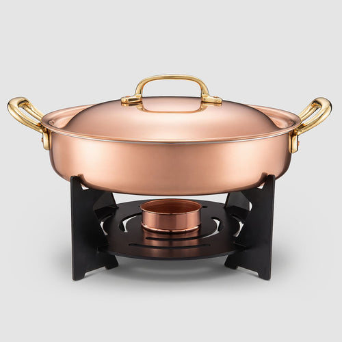 Copper pot with gold handles on a stand against a light gray background