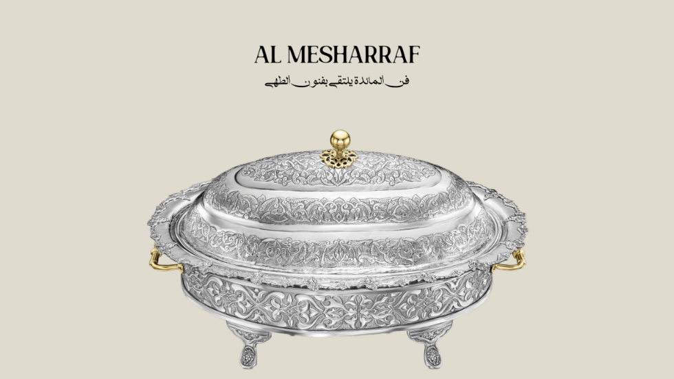 Decorative silver dish with a lid on a beige background, featuring the brand 'Al Mesharraf'.